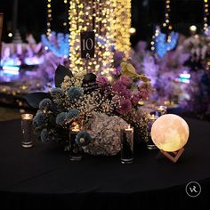 a table topped with candles and flowers next to a night sky light display filled with lights