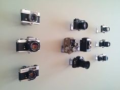 several different types of cameras hanging on the wall next to each other with their respective lens size