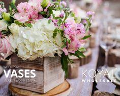 a wooden box filled with white and pink flowers on top of a purple table cloth