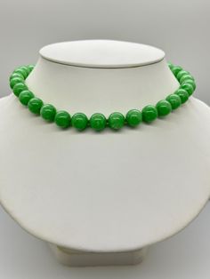 Green Jade Jadeite Bead Necklace.  This hand knotted necklace features 32 Green Jade Jadeite Beads Round Polished Grade AAA 11.9 to 12.4mm.  I hand knotted these with green silk thread and finished them with a 925 Silver Fold Over Magnetic Clasp.  The necklace measures 18 inches in length.  Please keep in mind that large beads take up space on the neck and they will fit tighter than an 18 inch chain.  The Beads are Genuine and Natural in color, no treatments.  The necklace pictured is the one you will receive.   It will arrive in a nice presentation box with a Certificate of Authenticity.   Please visit our Shop for more Pearls and Gemstone Jewelry. Classic Green Gemstone Beads Necklace, Classic Green Jewelry With 8mm Beads, Classic Green Single Strand Necklace, Formal Green Single Strand Beaded Necklace, Single Strand Jade Beaded Necklace With Round Beads, Elegant Single Strand Green Beads, Elegant Green Single Strand Beads, Green Beaded Necklaces With 8mm Round Beads, Round Green Beaded Necklaces With 8mm Beads