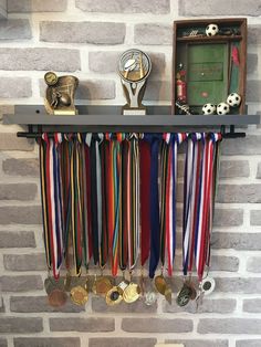 a bunch of medals are hanging on a brick wall next to a plaque and trophy