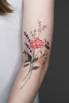 a woman's arm with flowers and leaves tattooed on the left side of her arm