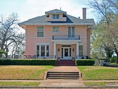 a large pink house sitting on the side of a road