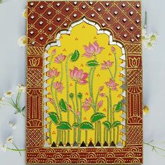 an intricately decorated card with pink flowers on yellow and red background, surrounded by small white flowers