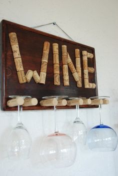 three wine glasses hanging on a wall with the word wine spelled out in corks