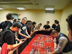 a group of people standing around a red table playing roulega on the floor