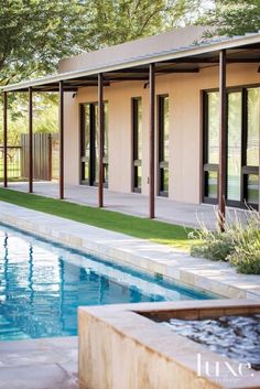 an outdoor swimming pool surrounded by trees and grass with doors open to the outside area