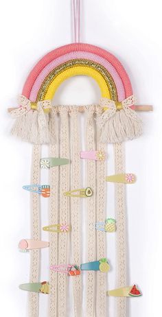 a wall hanging made out of fabric and wooden pegs, with a rainbow on it