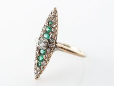 This Victorian cocktail ring features .42 carats of diamonds and .18 carats of round cut emeralds that are set in 14 karat yellow gold. The shape of the ring is a very long and slender marquise shape that runs down the finger. The primary diamond sits above the rest of the stones and weighs .22 carats. This is an elegant cocktail ring that has a very regal and historic look and would make a terrific gift!Composition: 14 Karat Yellow GoldRing Size: 5.75Primary Stone: Genuine Natural DiamondShape Green Cluster Ring With Rose Cut Diamonds, Green Diamond Ring With Rose Cut Diamonds, Fine Jewelry Marquise Cut Emerald Ring With Diamond Accents, Marquise Emerald Diamond Ring In Yellow Gold, Yellow Gold Marquise Emerald Ring With Diamonds, Marquise Cut Emerald Ring With Diamond Accents, Cluster Emerald Ring With Diamond Accents, Heirloom Green Diamond Ring With Single Cut Diamonds, Wedding Emerald Ring With Pave Setting In 14k Gold