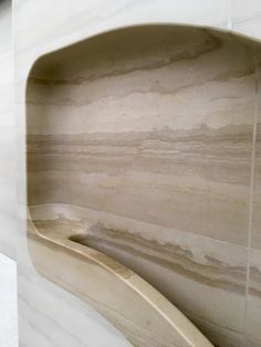 a bathroom with marble walls and flooring next to a urinal in the wall