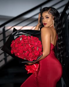 a woman in a red dress holding a large bouquet of roses on her left shoulder