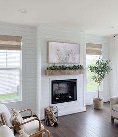 a living room with white walls and wood floors, two couches and a fireplace