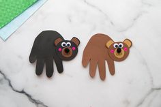 two hand puppets made to look like bears on a marble table with scissors and paper