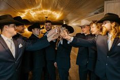 a group of men in suits and hats are holding wine glasses up to each other