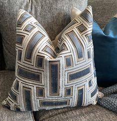 two pillows sitting on top of a couch next to a pillow case with blue and white designs