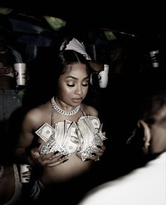 a woman holding money in her hands while standing next to other people at a party