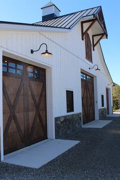 a white barn with two brown garage doors