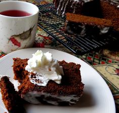 a piece of cake on a plate next to a cup of tea