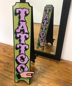 a sign that says taco and pointing at it in front of a mirror with the word taco painted on it