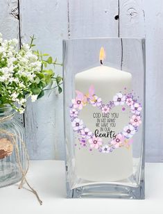 a white candle sitting on top of a table next to a vase filled with flowers