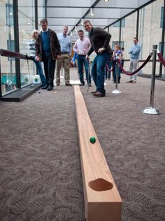 several people are standing around and looking at an object on the ground that looks like a long piece of wood