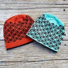 two knitted hats sitting on top of a wooden table