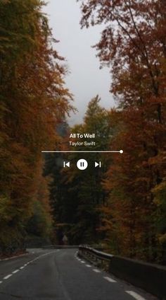 the road is surrounded by trees with orange and yellow leaves on it, as well as an audio player