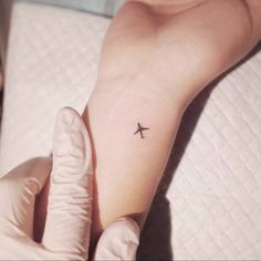 a small airplane tattoo on the wrist