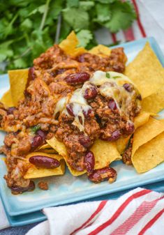 chili and cheese nachos on a plate with tortilla chips next to it