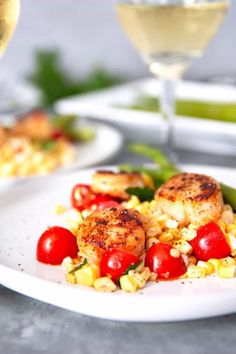 shrimp and corn salad on a white plate with a glass of wine in the background