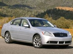 the silver car is parked on the side of the road in front of some mountains