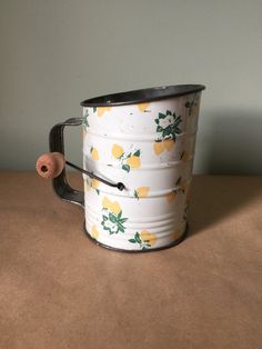 a white and yellow tin can with lemons on it sitting on top of a table