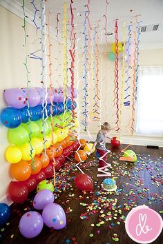 balloons and streamers are on the floor in front of a wall with confetti