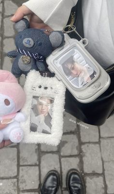 a person holding two small stuffed animals and a cell phone in their left hand,