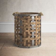 a wooden basket sitting on top of a hard wood floor next to a white wall