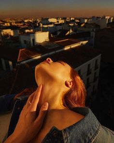 a woman with her eyes closed standing on top of a building looking up at the sky