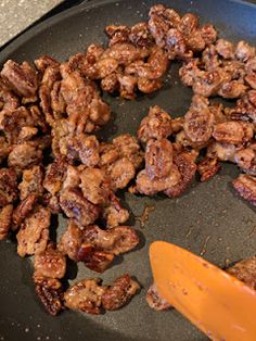 some meat and cheese are being cooked in a skillet with a spatula on the side