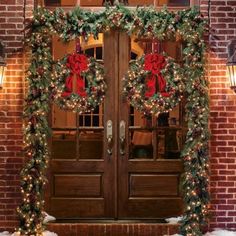 two christmas wreaths on the front door of a brick building with lights and decorations