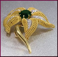 "The captivating flower brooch has a center oval shaped 10.00 ct deep forest green tourmaline. It dates from the 1960's. It is surrounded by 4 gold coiled leaves encrusted with 1.75 ct of round diamonds in the center of each leaf. It all gracefully blooms out of the golden stem. This is enticing appeal all swathed up into a pin. The pin weighs 45 grams. It measures 2 ½ \" long and 2\" wide at its widest point. P 518S SIX MONTH LAY-AWAY AVAILABLE - PLEASE CONTACT ME TO SET UP A PLAN" Elegant Green Gemstone Brooch, Elegant Green Gemstone Brooches, Green Fine Jewelry Brooch For Anniversary, Fine Jewelry Green Brooches For Anniversary, Green Fine Jewelry Brooches For Wedding, Fine Jewelry Green Brooch For Anniversary, Elegant Green Oval Brooches, Green Oval Brooches For Formal Occasions, Brooch Diamond