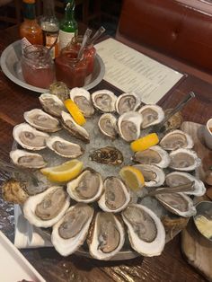 a platter filled with oysters on top of a wooden table next to condiments