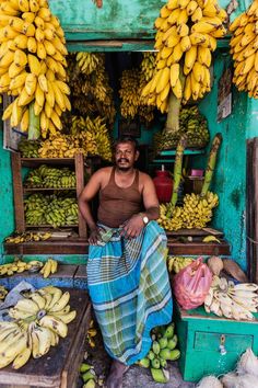 a man is sitting in front of his fruit stand