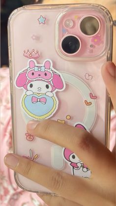 a person holding up a phone case with stickers on it