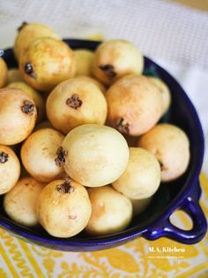 a blue bowl filled with yellow fruit on top of a white and yellow table cloth