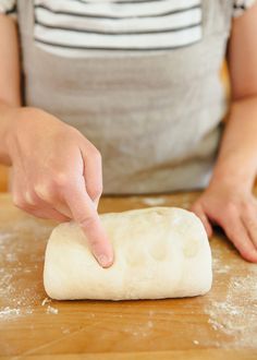 a person kneading dough on top of a wooden table