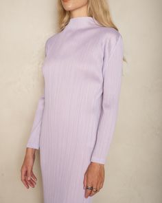 Turtleneck dress by Pleats Please Issey Miyake. A classic Pleats Please mid-length silhouette in radiant soft purple. Finished with an elegant lifted neckline and long sleeves. Signature vertical pleating with crisp and angular sleeve seams that can be folded completely flat for storage. 100% Polyester.Made in Japan. Pictured with Tapestry Low Tennis Shoes by Uma Wang. Elegant Stretch Purple Midi Dress, Elegant Purple Stretch Midi Dress, Purple Long Sleeve Formal Dress, Purple Long Sleeve Dress For Formal Occasions, Pleated Long Sleeve Stretch Midi Dress, Long Sleeve Pleated Stretch Midi Dress, Long Sleeve Stretch Pleated Midi Dress, Purple Long Sleeve Dress For Winter, Fitted Mauve Midi Dress