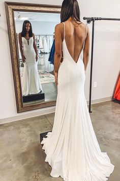 the back of a woman's white dress in front of a mirror