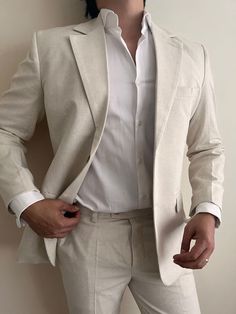 a man in a white suit is posing for the camera with his hands on his hips