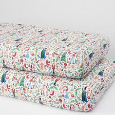 two pillows are sitting side by side on a white surface with christmas decorations all over them