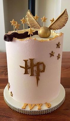 a pink cake with gold stars and a harry potter crest on top