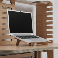 an open laptop computer sitting on top of a wooden desk next to a shelf with shelves